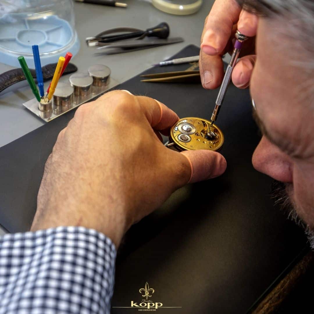 Uhrmacher repariert eine Uhr an einem Tisch mit Utensilien